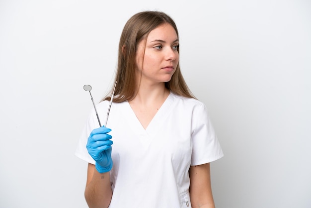 Mulher dentista segurando ferramentas isoladas no fundo branco, olhando para o lado