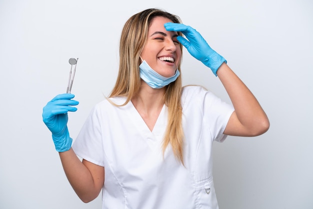 Mulher dentista segurando ferramentas isoladas no fundo branco sorrindo muito