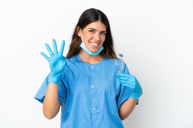 Mulher dentista segurando ferramentas sobre um fundo branco isolado feliz e contando quatro com os dedos