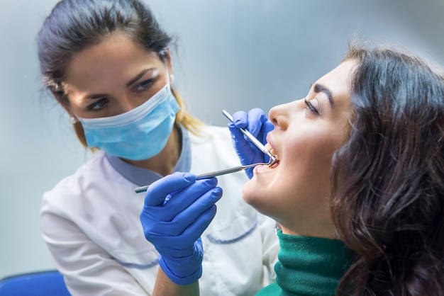 Mulher dentista trabalhando estomatologista segurando sonda atendimento odontológico de baixo custo