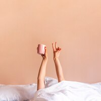 Foto mulher dentro da cama com as mãos para cima