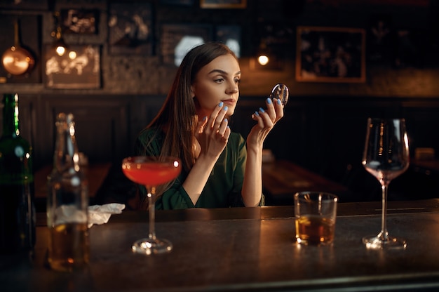 Mulher deprimida bebe álcool no balcão do bar