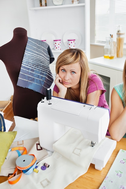 Mulher deprimida, costurando roupas na cozinha