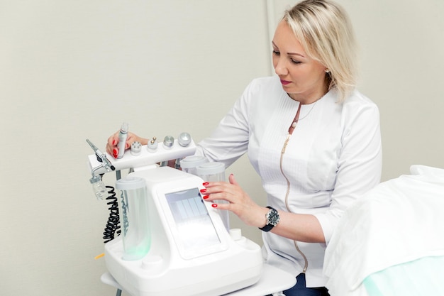 Mulher dermatologista posando em seu escritório com uma máquina de beleza