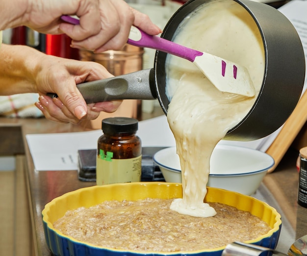 Mulher derrama massa na forma de bolo de banana na cozinha de casa