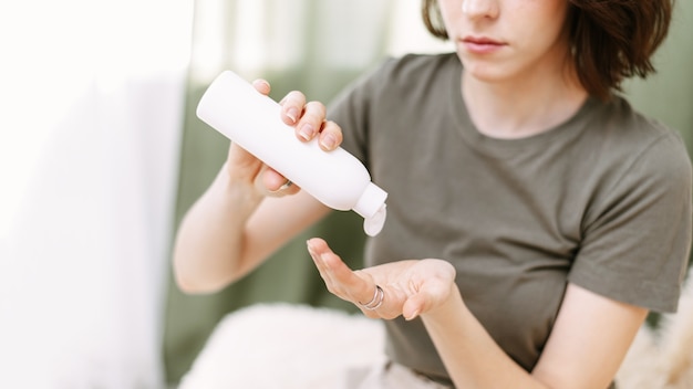 Mulher derramando loção ou creme para as mãos do frasco na mão. conceito de cuidados com a pele. banner da web