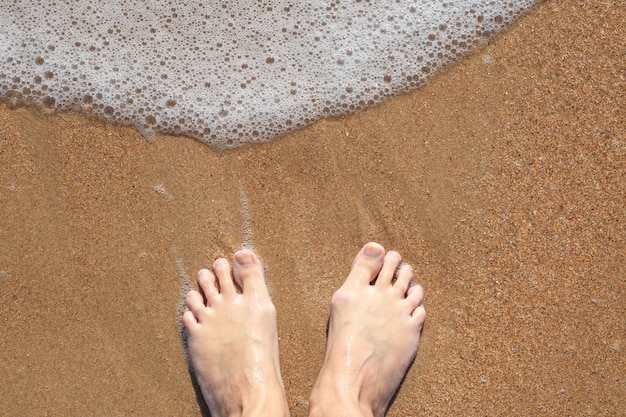 Mulher descalça na areia com espuma do mar