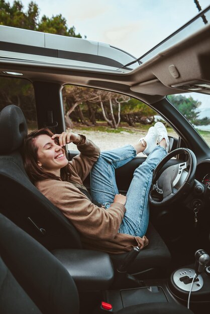 Foto mulher descansando no carro estacionado na praia do mar. férias de verão