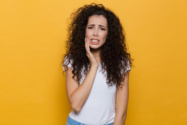 Mulher descontente com dor de dente isolada em amarelo.