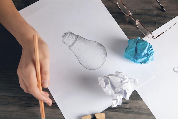 Mulher desenhando uma lâmpada no papel