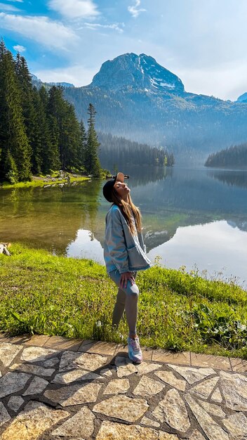 Foto mulher desfrutando da beleza da natureza olhando para um lago de montanha em montenegro