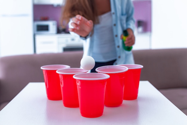 Mulher desfrutando de jogo de pong de cerveja na mesa em casa