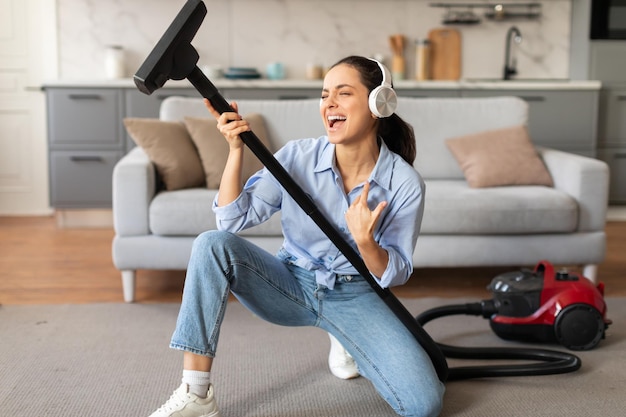 Foto mulher desfrutando de música enquanto segura um aspirador