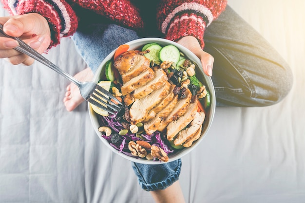 Mulher desfrutando de salada de peito de frango em casa