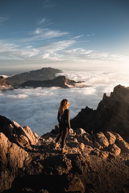 mulher desfrutando de um belo pôr do sol do topo do Roque De Los Muchachos com um mar de nuvens