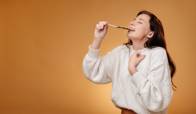 Mulher desfrutando de um doce verde mordendo no conceito de comida doce de fundo amarelo para o Natal