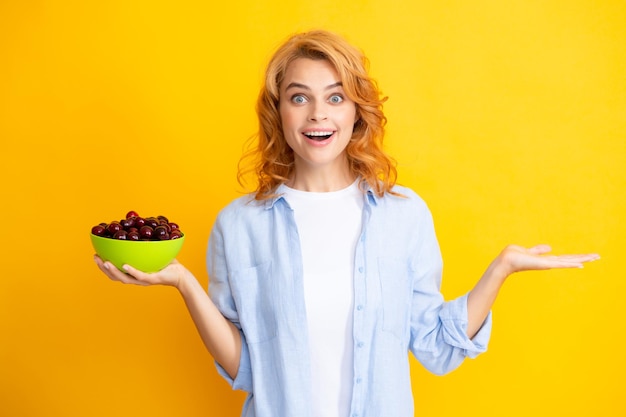 Mulher desfrutando de uma cereja doce fresca Fêmea comendo cerejas em fundo amarelo