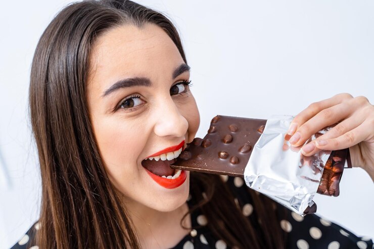 Foto mulher desfrutando de uma mordida de delicioso chocolate uma mulher mordendo uma barra de chocolate