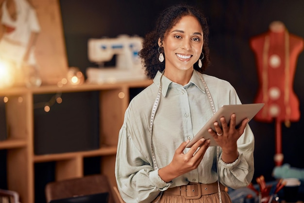 Mulher designer de moda e tablet em oficina de fabricação de estúdio de varejo ou pequena empresa sorriso de retrato e costureira feliz com tecnologia digital para inovação ou visão de idéias de roupas