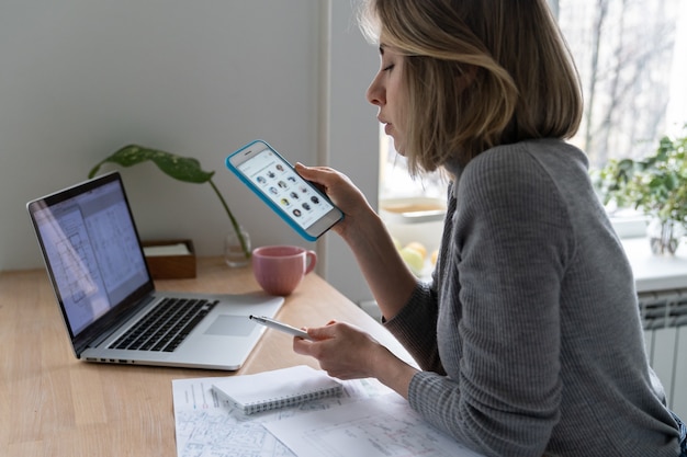 Mulher designer usando smartphone, faz uma pausa no trabalho e ouve um palestrante no clube