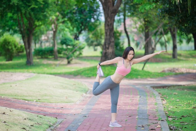 Mulher desportiva asiática esticando o corpo respirando ar fresco no conceito de exercício de pessoas do parqueTailândia
