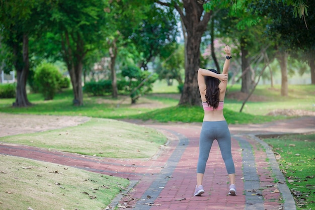 Mulher desportiva asiática esticando o corpo respirando ar fresco no parqueTailândia pessoasFitness e conceito de exercício
