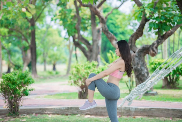 Mulher desportiva asiática esticando o corpo respirando ar fresco no parqueTailândia pessoasFitness e conceito de exercício