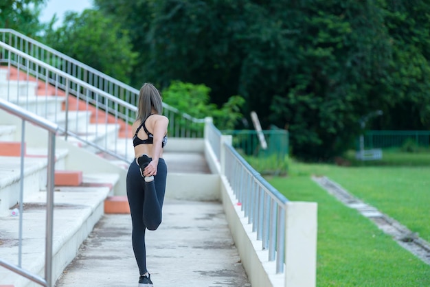 Mulher desportiva asiática esticando o corpo respirando ar fresco no parquetailândia pessoasfitness e conceito de exercíciocorrer no parque