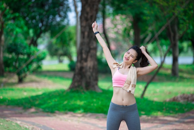 Mulher desportiva asiática esticando os braços respirando ar fresco no parqueTailândia pessoas exercitam conceito