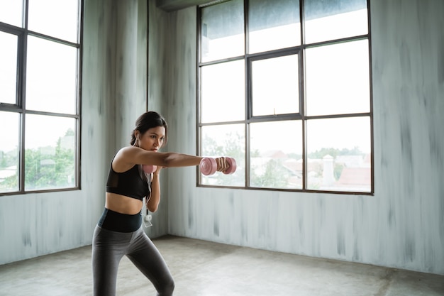 Mulher desportiva com haltere fazendo exercício de peso