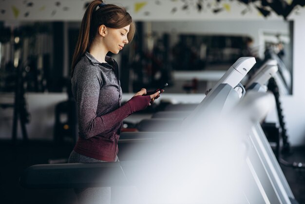 Mulher desportiva correndo na esteira na academia