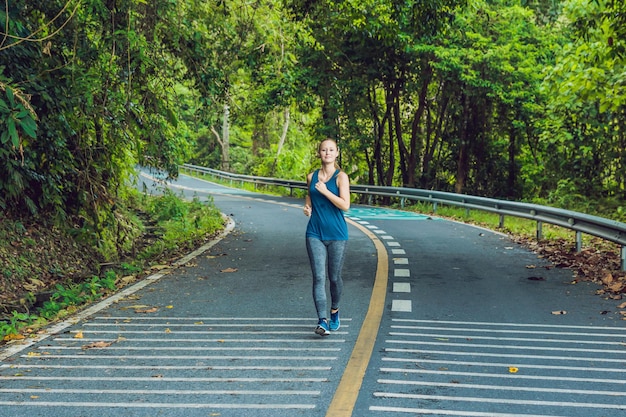 Foto mulher desportiva correndo na estrada ao nascer do sol. conceito de bem-estar de fitness e treino