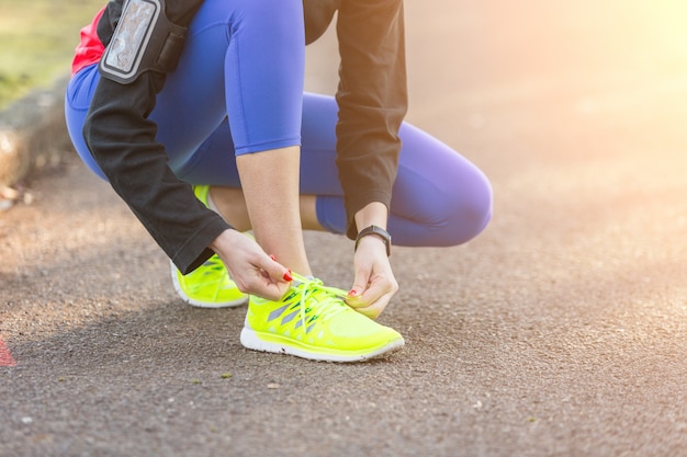 Mulher desportiva nova que faz acima de suas sapatas antes de correr.