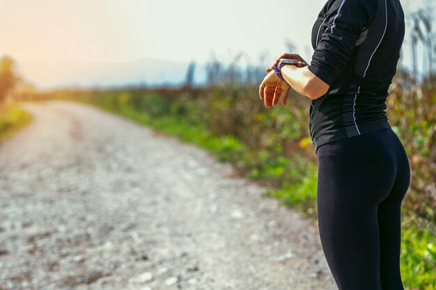 Foto mulher desportiva nova que verifica o perseguidor do smartwatch