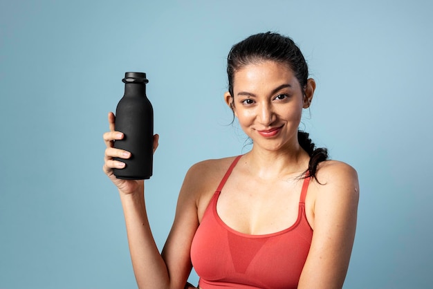 Foto mulher desportiva segurando uma garrafa preta