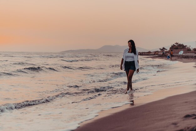 Foto mulher despreocupada feliz apreciando o belo pôr do sol na praia. foco seletivo. foto de alta qualidade