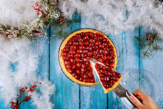 Mulher detém pedaço de torta de cereja na mesa com decoração de Natal.