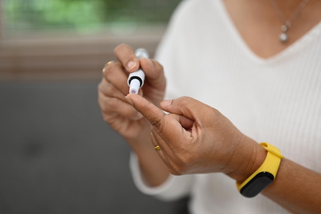 Mulher diabética madura a recolher amostra de sangue com caneta lancet para verificar o nível de açúcar no sangue Conceito de cuidados de saúde para o diabetes