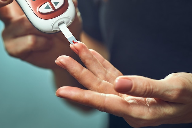 Mulher diabética usando medidor de glicose no sangue, mãos femininas segurando lanceta caneta glicosímetro no dedo medir açúcar verificar insulina