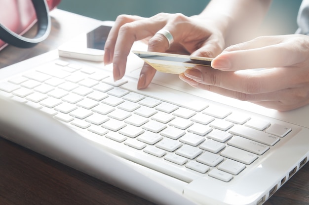 Mulher digitando no teclado do laptop e segurando cartão de crédito, conceito de compras on-line