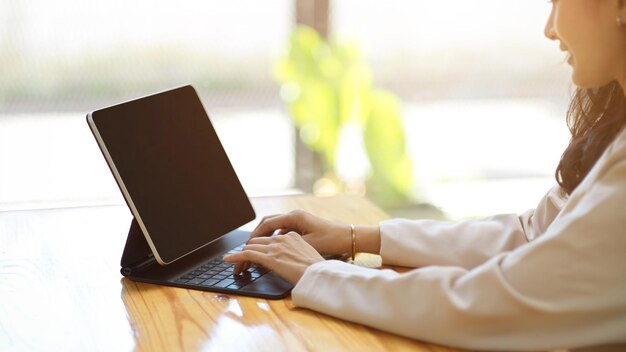 Mulher digitando no teclado sem fio do tablet trabalhando no trabalho remoto do tablet no café