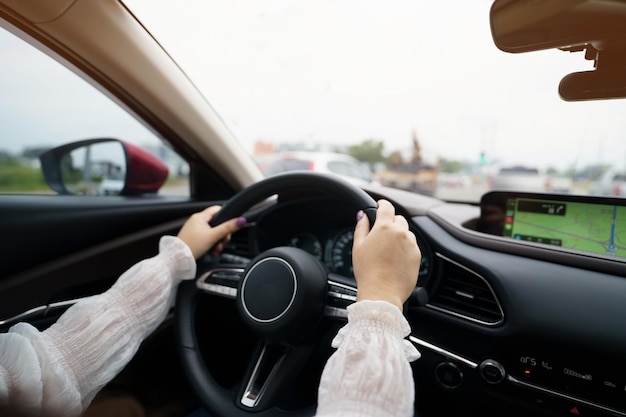 Mulher dirigindo carro se sentindo feliz em dirigir segurando o volante e olhando na estrada