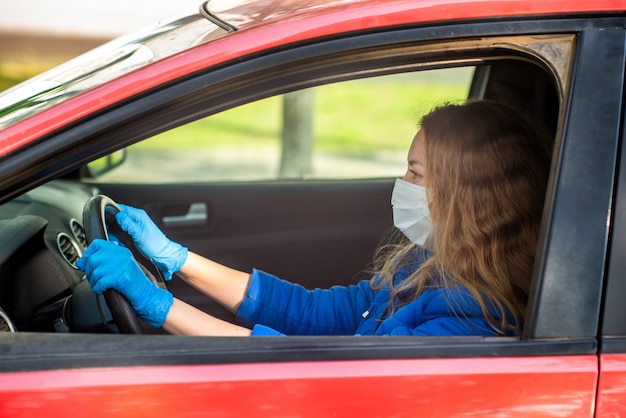 Mulher dirigindo um carro em luvas e máscara médica protetora. Estilo de vida e condução segura durante um coronavírus pandêmico