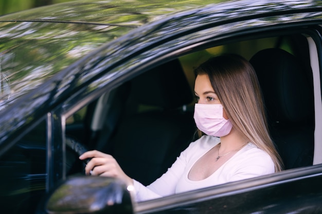 Mulher dirigindo um carro usando máscara médica estéril
