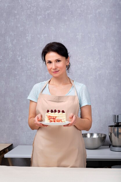 Mulher do chef de pastelaria tem um bolo com frutas.