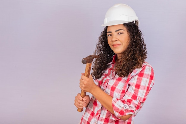 Mulher do empreiteiro segurando um martelo sorrindo sobre fundo branco.