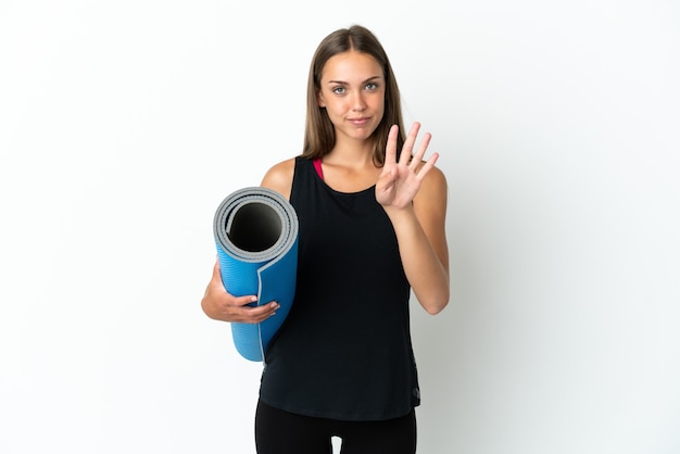 Mulher do esporte indo para as aulas de ioga, segurando um tapete sobre um fundo branco isolado feliz e contando quatro com os dedos