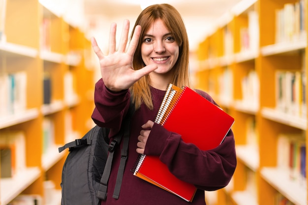 Mulher do estudante que conta cinco no fundo unfocused. de volta à escola