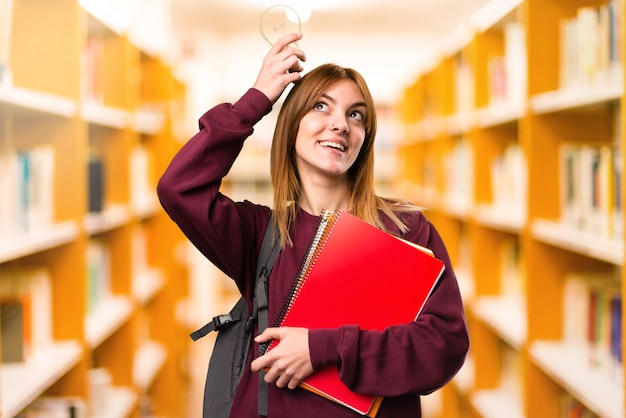 Mulher do estudante que guarda um bulbo em fundo unfocused. de volta à escola