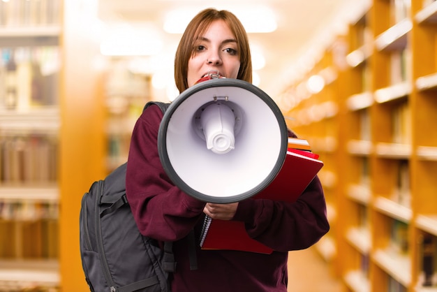 Mulher do estudante que guarda um megafone em fundo unfocused. de volta à escola